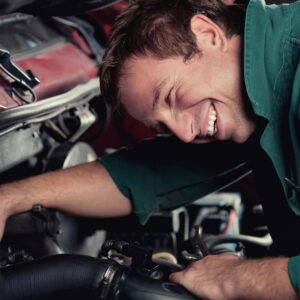 A smiling mechanic working on an engine